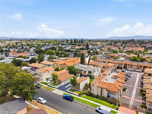 Wide aerial of 12582 Adelle showing the building rooftop, driveway, and the surrounding low-density residential pattern of West Garden Grove