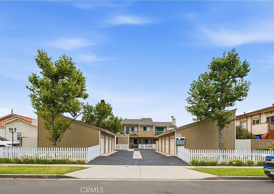 Streetfront view of 12582 Adelle with the white picket fence, the central driveway, and the garage rows that line each side of the parcel